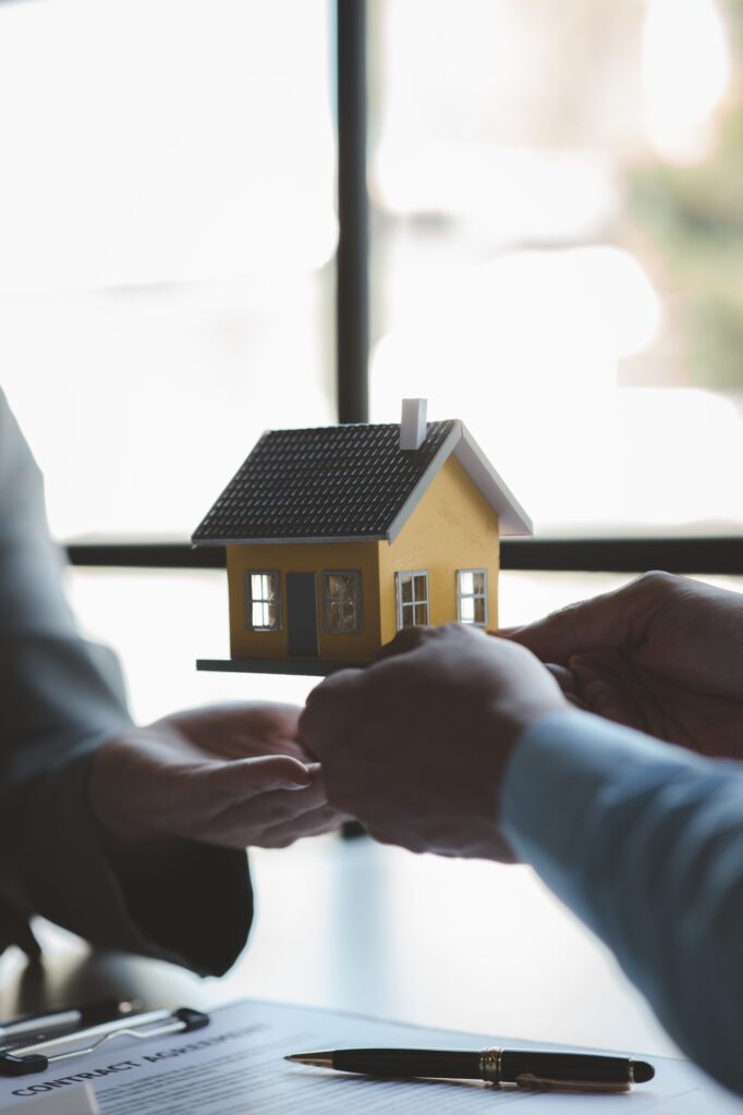A housing salesman holds a model of a house and sends it to customers as an example.